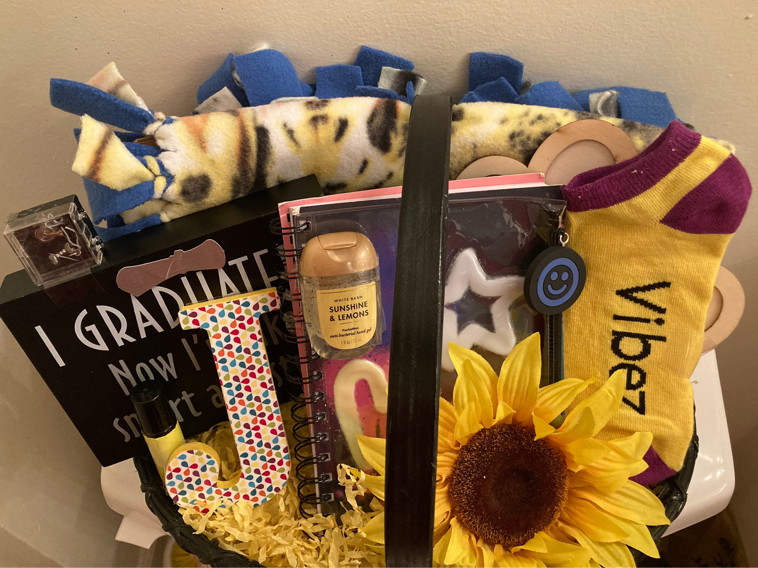 Gift basket with various items including socks, a sunflower, graduation sign, and a journal.