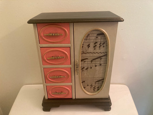 Small cabinet with pink drawers and a decorative glass panel on a white surface.